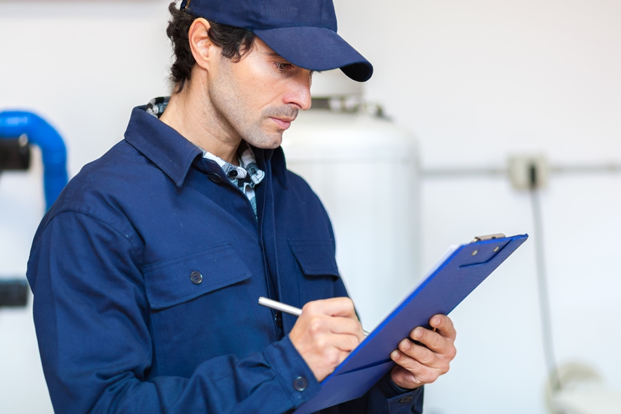 A maintenance worker taking notes on a clipboard | Schedule Your Annual Furnace Inspection Now | Fort Wayne, IN