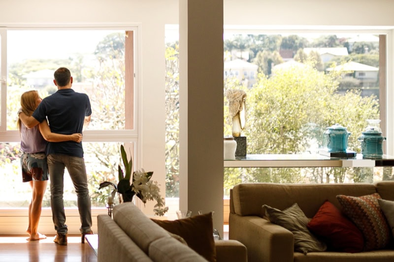 Installing New HVAC Equipment? Consider These Tips! Photo of a couple admiring the view from their living room window.