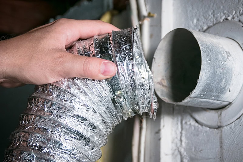 Breathe Easy This Holiday Season: Why Duct Cleaning Matters. Photo of someone taking a part an air vent to clean.